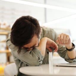 Man sneezing into his elbow at an indoor coffee shop.
