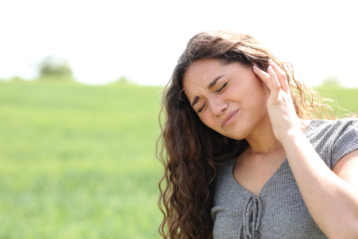 Woman holds ear in a park