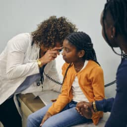 Young girl holding her mom's hand during an ear exam