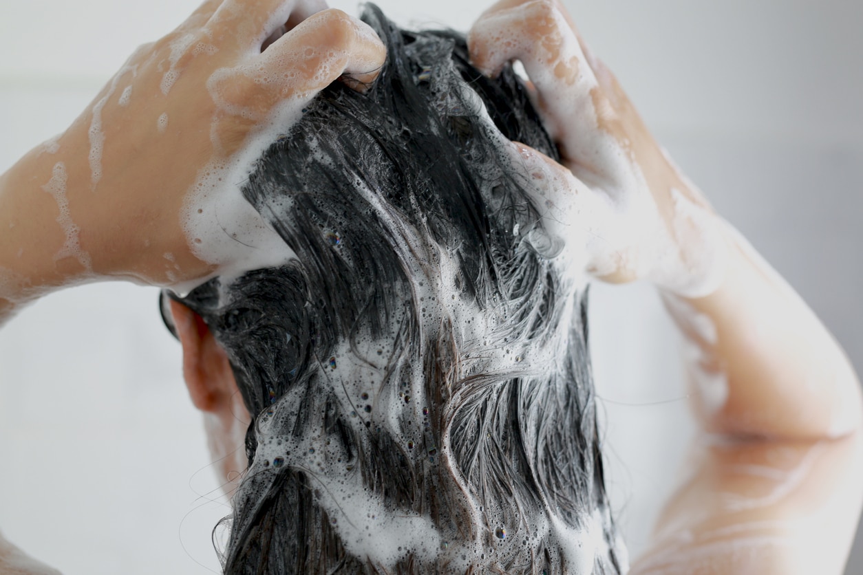 Woman is washing her hair with shampoo.
