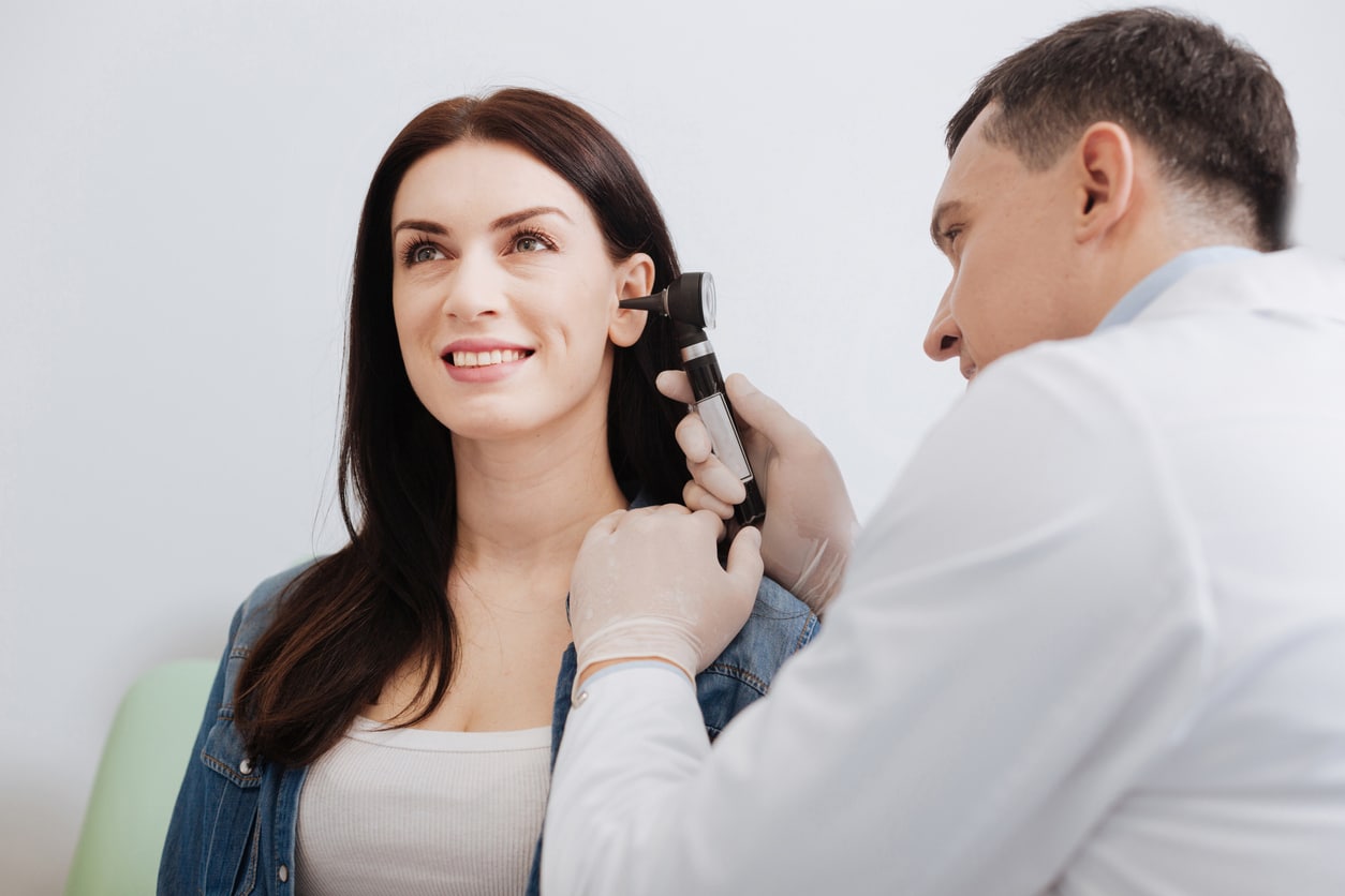 ENT conducting an ear exam on a young woman.