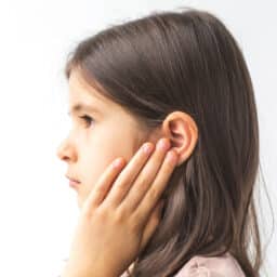 Young girl with her hand on her ear looking upset