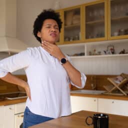 Woman at home holding her sore throat