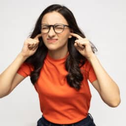 Young woman on a white background plugging her ears