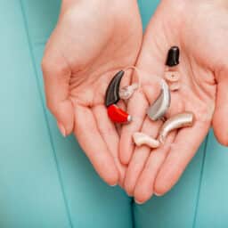 Different types of hearing aids in female hands, top view.