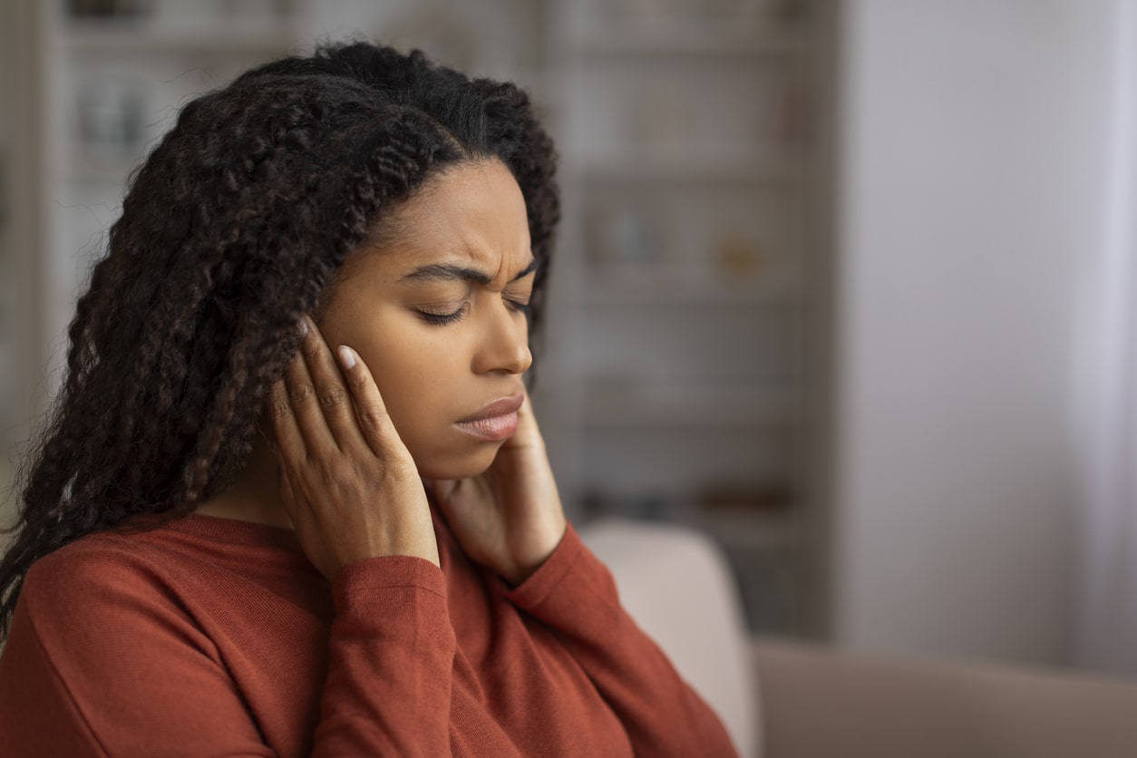 Stressed woman holding her ears.