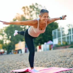Woman practicing yoga outdoors, standing on one foot