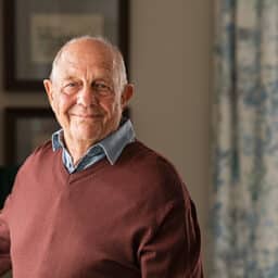 Senior man standing in his home, looking happy.