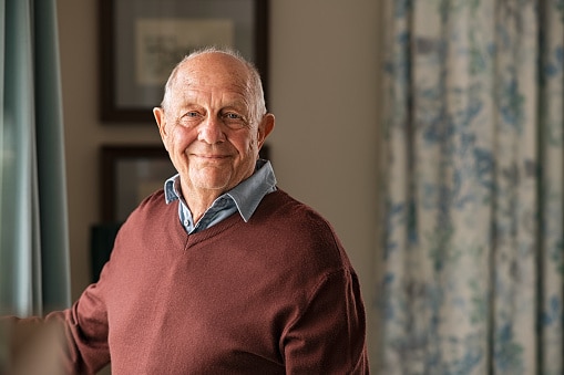 Senior man standing in his home, looking happy.
