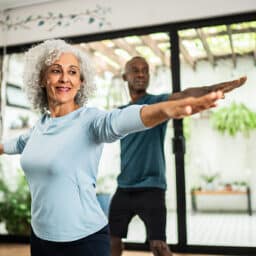 A senior man and woman doing yoga at home.