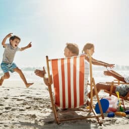 Beach, sunshine and family with vacation, happiness and excited with getaway trip, chairs and playful.