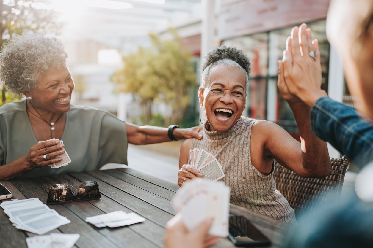 Senior friends smiling and playing cards.