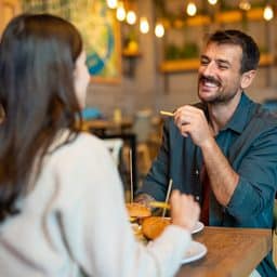 Happy couple sitting in the restaurant having lunch, smiling, enjoying being together.