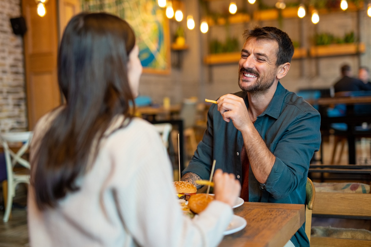 Happy couple sitting in the restaurant having lunch, smiling, enjoying being together.