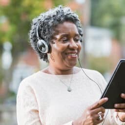 Senior woman listening to her audiobook while following along on her e-reader.